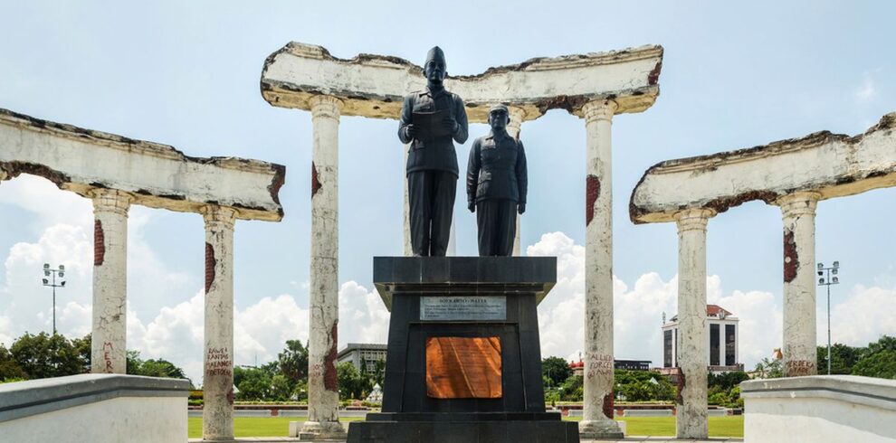 The iconic Tugu Pahlawan in Surabaya, a towering monument dedicated to the heroes of Indonesia's independence, set against the clear blue sky and surrounded by a large open plaza.