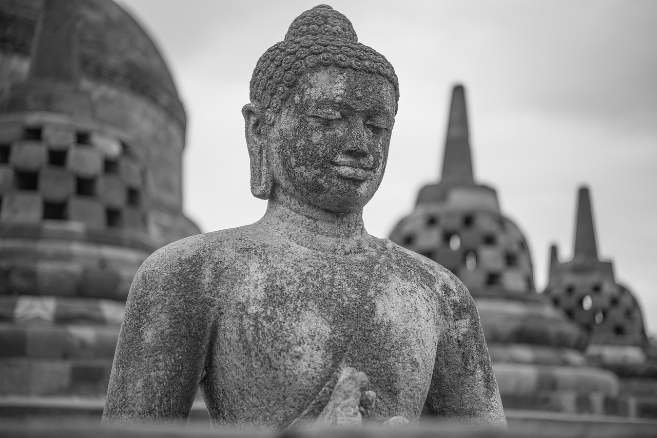 Close-up of a stone Buddha statue at Borobudur Temple, showcasing intricate details and serene expression, surrounded by ornamental carvings.