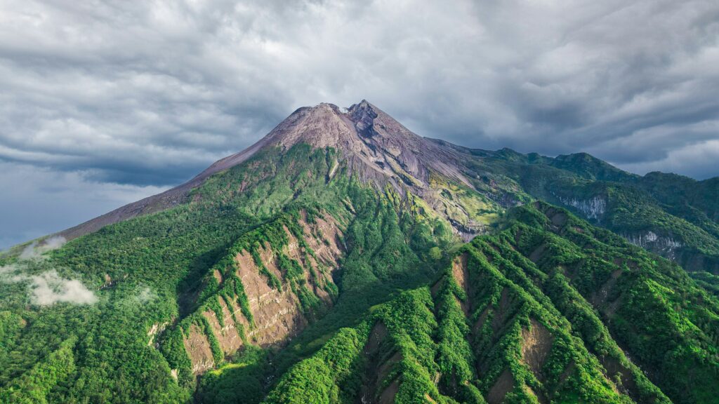 Clear view of Mount Merapi with its majestic volcanic peak towering against a bright blue sky, highlighting the rugged terrain and natural beauty.