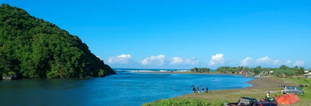 Tranquil view of Muara Mbaduk in Banyuwangi where the river flows into the ocean surrounded by greenery